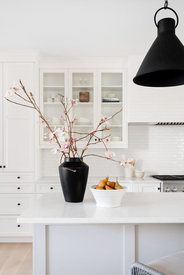 white kitchen with cherry blossoms in a black vase